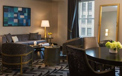 Lounge within a guest room of The Allegro Royal Sonesta Hotel Chicago Loop, including sofa, armchairs, coffee tables, and a window.
