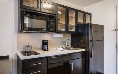 Sonesta Simply Suites Atlanta Gwinnett Place guest room kitchen, furnished with microwave, hob, oven, sink, and fridge-freezer.