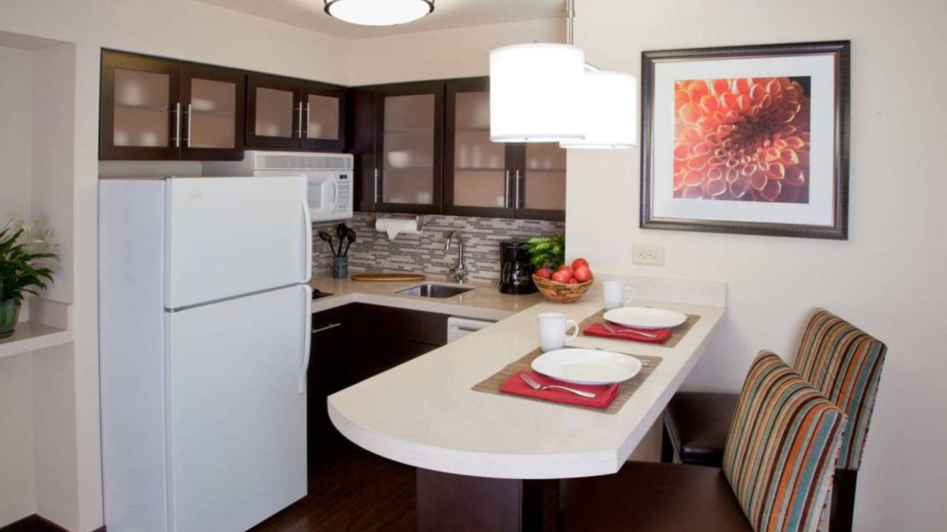 Sonesta ES Suites Atlanta Alpharetta Avalon guest room kitchen, including fridge-freezer, microwave, and kitchen table with two chairs.