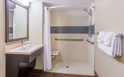 Guest bathroom in Sonesta ES Suites Atlanta Alpharetta Avalon featuring shower with curtain, mirror, and sink.