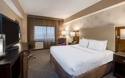 Double bed guest room in Sonesta White Plains Downtown, featuring window, armchair, and TV.