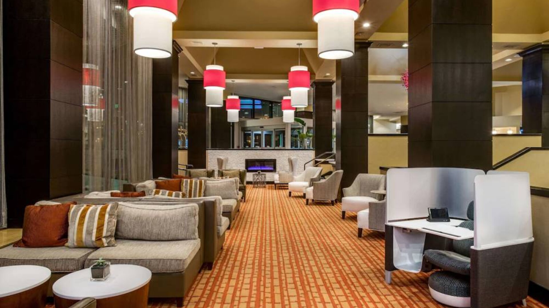 Sonesta White Plains Downtown’s lobby lounge is furnished with sofa and armchair seating, coffee tables, and a fireplace.