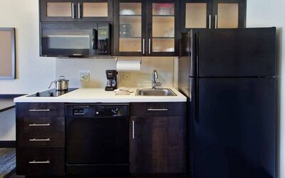 Guest room kitchen in Sonesta Simply Suites Oklahoma City Airport, furnished with microwave, hob, and fridge-freezer.