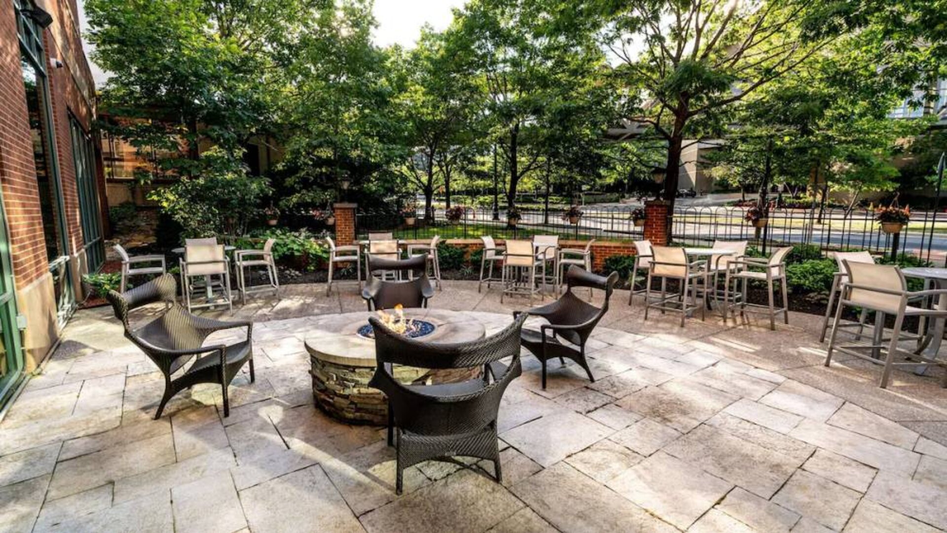 Sonesta Columbus Downtown’s patio features a fire pit that is surrounded by chairs with more tables and chairs nearby.