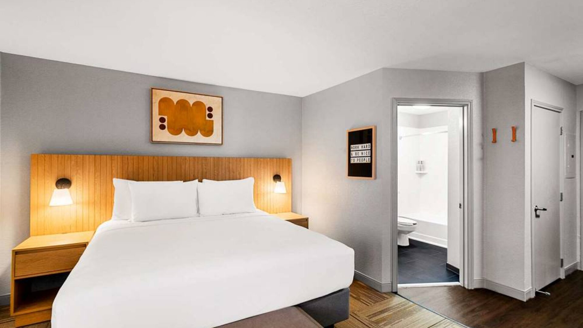 Double bed guest room in Sonesta Simply Suites Austin South, featuring art on the wall and an ensuite bathroom.