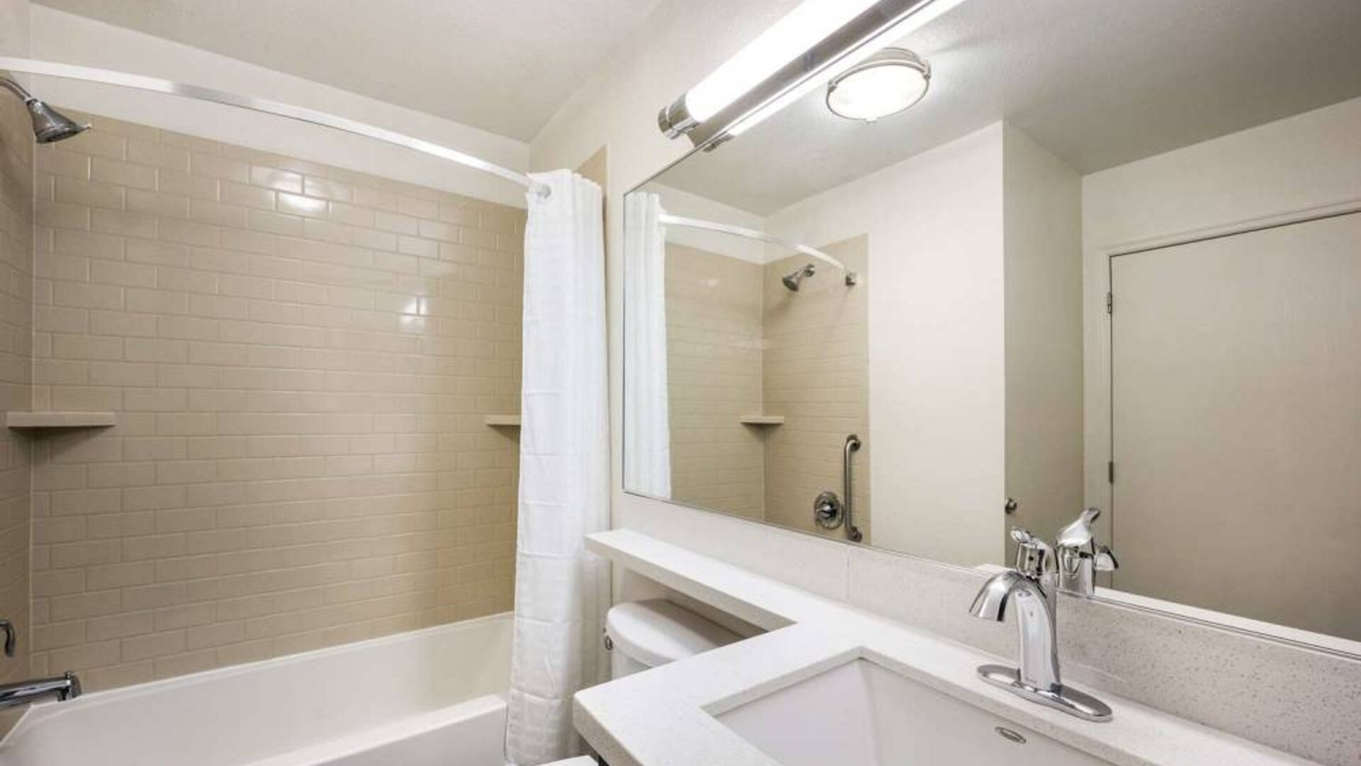 Guest bathroom in Sonesta Simply Suites Austin The Domain Area, featuring bath with a shower, lavatory, mirror and sink.