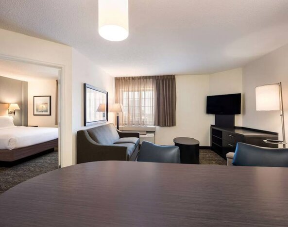 Double bed guest room in Sonesta Simply Suites Houston CityCentre I-10 West, including a living area furnished with a TV, sofa, and coffee table.