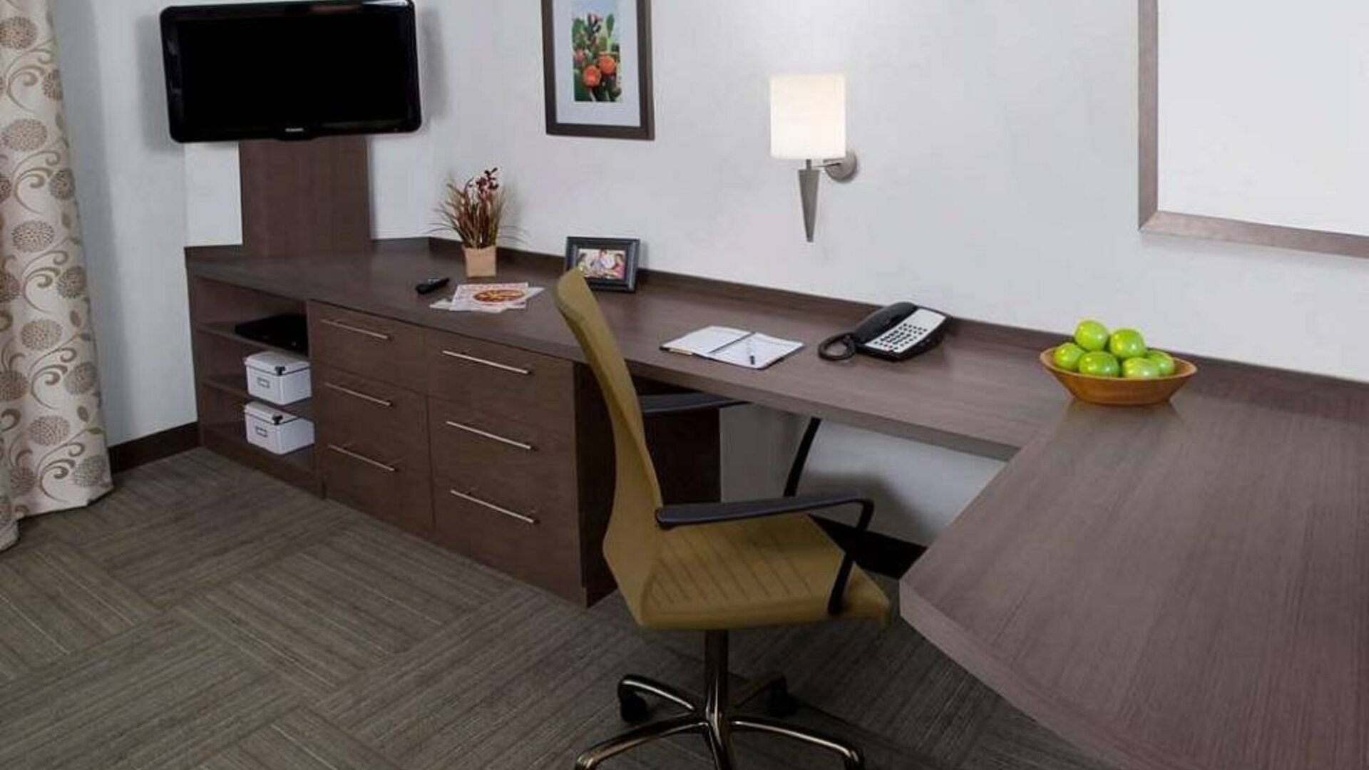 Guest room workspace in Sonesta Simply Suites Houston CityCentre I-10 West, featuring desk, chair, lamp, and telephone.