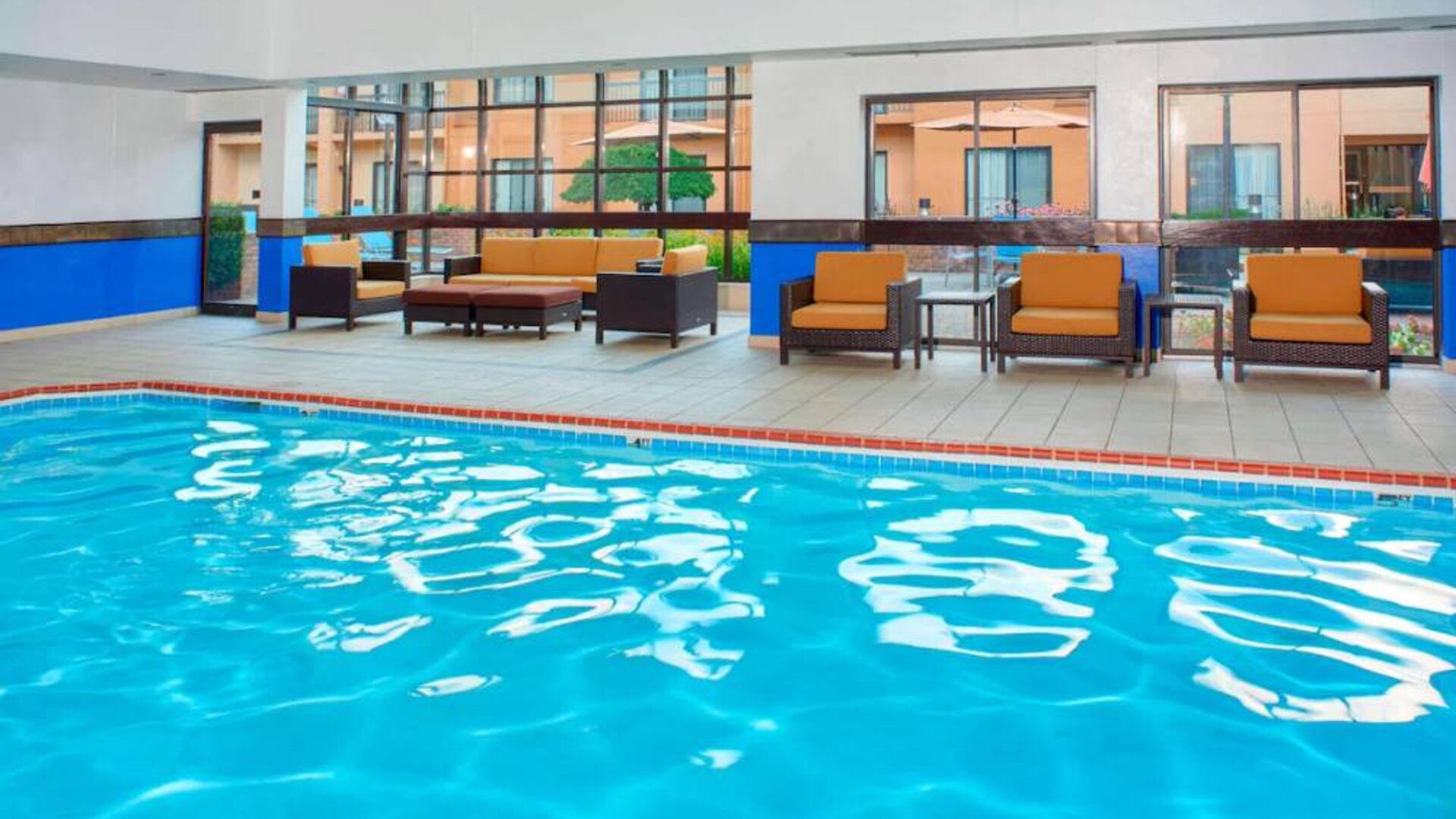 Sonesta Select Detroit Auburn Hills’ indoor pool has armchair and sofa seating by the side, plus large windows.