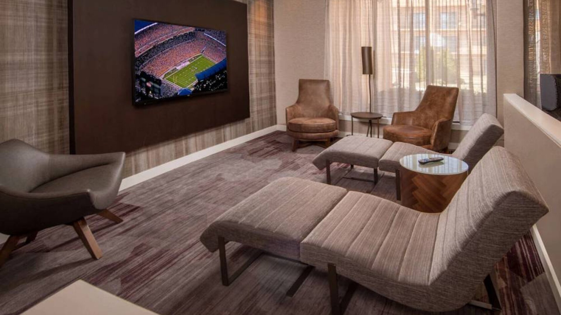 The hotel’s lobby features reclined seats facing a large, wall-mounted TV.