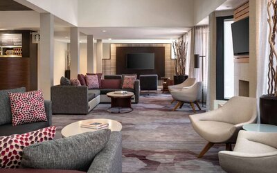 Lounge in the hotel lobby, furnished with comfy chairs and large sofas, coffee tables and multiple large televisions.