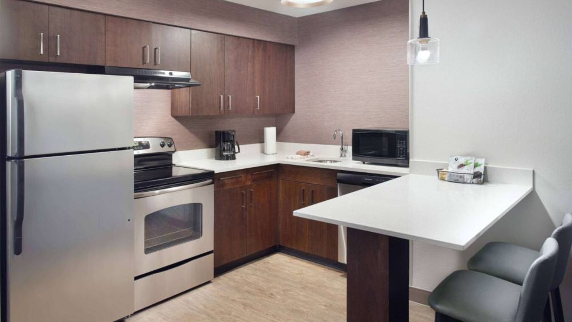 Sonesta ES Suites Raleigh Cary guest room kitchen, fitted with oven, microwave, fridge-freezer, and sink.