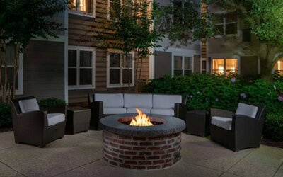 Sonesta ES Suites Fairfax Fair Lakes’ fire pit has armchairs, coffee tables, and a sofa where guests can relax and socialize.