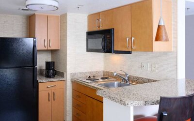 Sonesta ES Suites Dallas Medical Market Center guest room kitchen, with microwave, fridge-freezer, and hob.