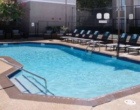 Sonesta ES Suites Dallas Medical Market Center’s outdoor pool has sun loungers as well as armchairs and coffee tables by its side.