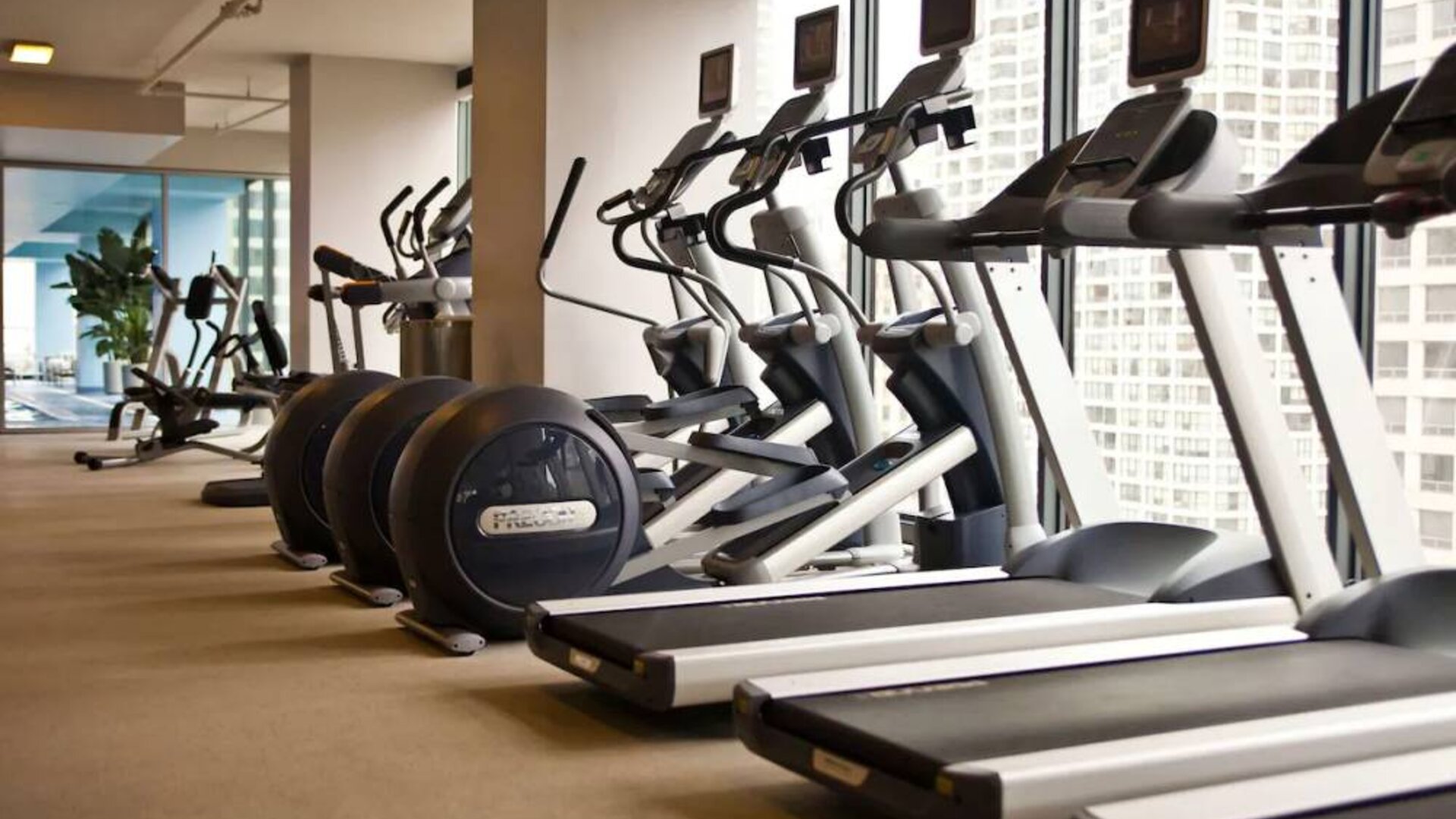 The hotel fitness center is equipped with a range of exercise machines, and large windows with city views.