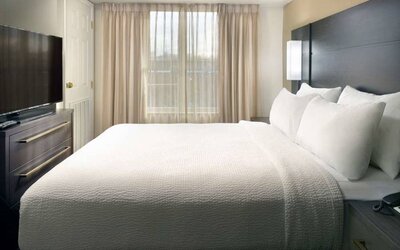 Double bed guest room with a window and large TV at Sonesta ES Suites Raleigh Durham Airport Morrisville.