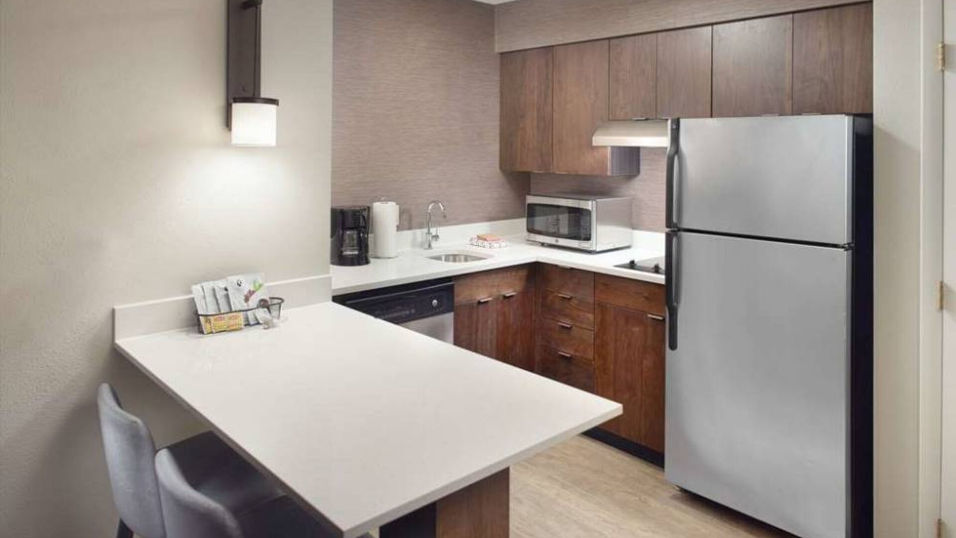 Guest room kitchen in Sonesta ES Suites Raleigh Durham Airport Morrisville, featuring fridge-freezer, hob, microwave, and table.