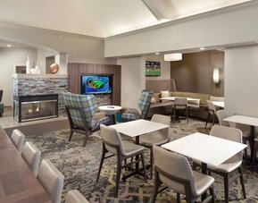 Lobby lounge furnished with sofa seating, tables and chairs, a fireplace and TV, at Sonesta ES Suites Raleigh Durham Airport Morrisville.