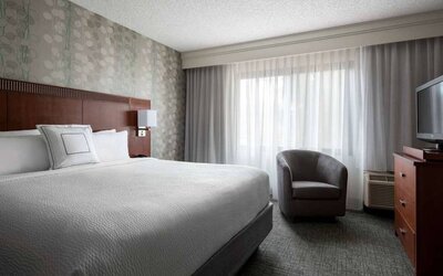 Double bed guest room in Sonesta Select Los Angeles LAX El Segundo, featuring armchair, window, and TV.