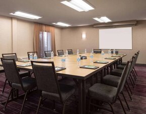 Hotel meeting room, with window, whiteboard, and seating for 14 around a large wooden table.