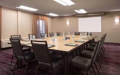 Hotel meeting room, with window, whiteboard, and seating for 14 around a large wooden table.