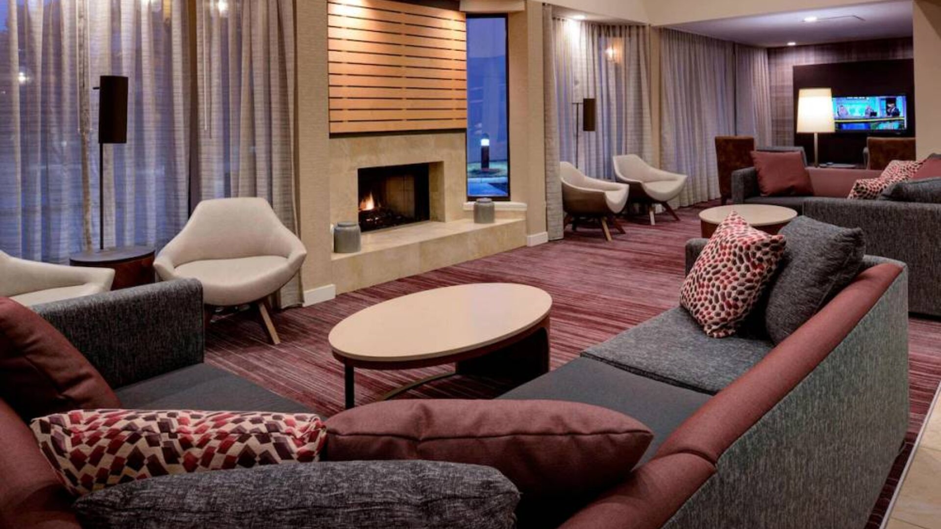 Sonesta Select Kansas City South Overland Park’s lobby lounge features a fireplace and wall-mounted TV, with extensive sofa seating and comfy chairs.