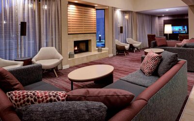 Sonesta Select Kansas City South Overland Park’s lobby lounge features a fireplace and wall-mounted TV, with extensive sofa seating and comfy chairs.