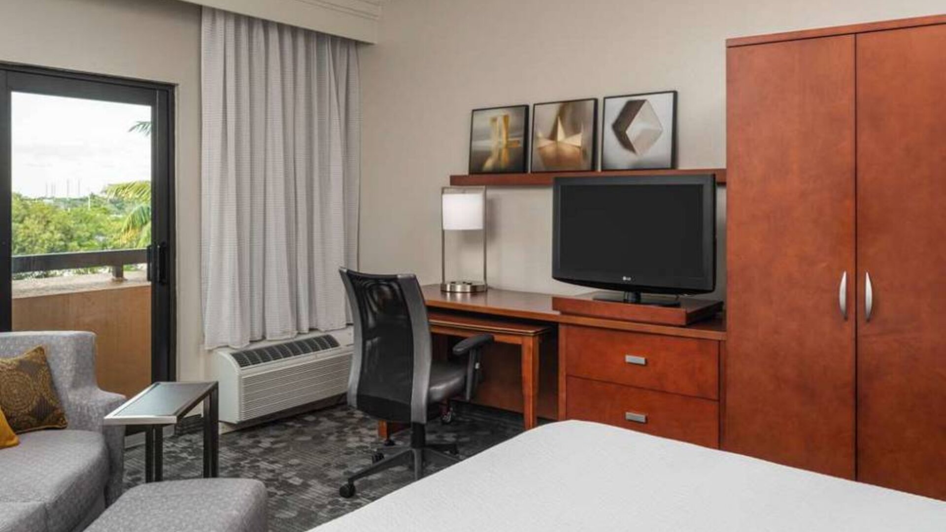 Sonesta Select Miami Lakes’ double bed guest room, with TV and a workspace desk, chair, and lamp.