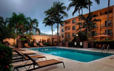 Outdoor pool a mix of sun loungers and shaded tables and chairs by the side, at Sonesta Select Miami Lakes.