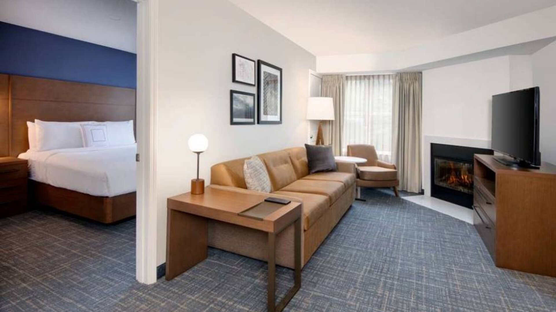 Guest room living area in Sonesta ES Suites Atlanta Alpharetta North Point Mall, with sofa, fireplace,  and TV.
