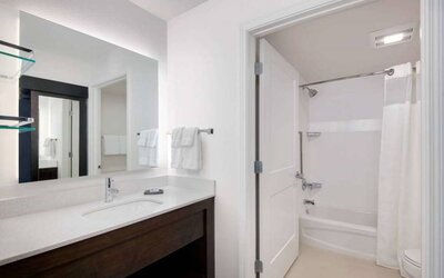Guest bathroom in Sonesta ES Suites Atlanta Alpharetta North Point Mall featuring shower-equipped bath, lavatory, mirror, and sink.