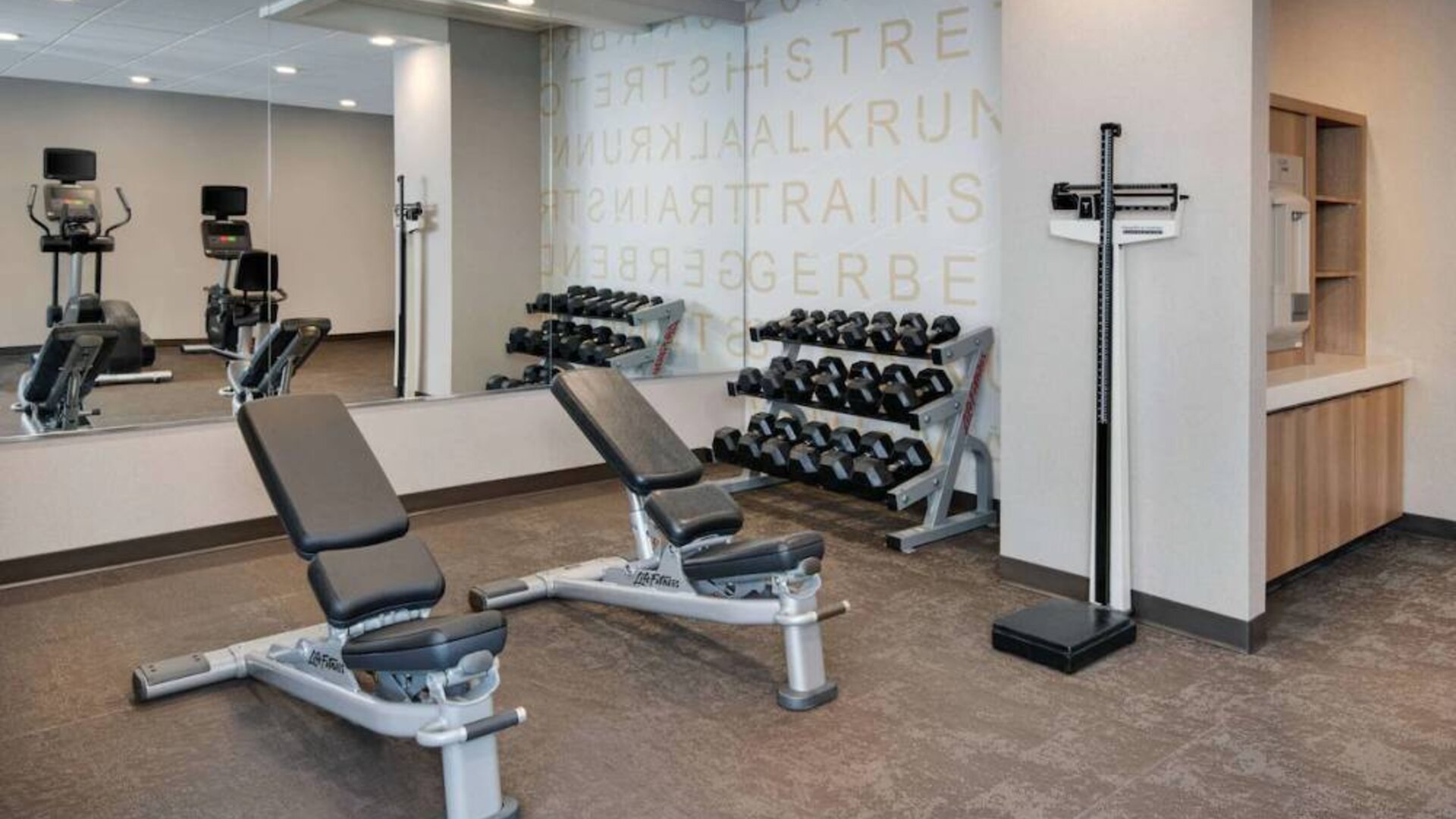 Hotel fitness center equipped with free weights, benches, and various exercise machines.