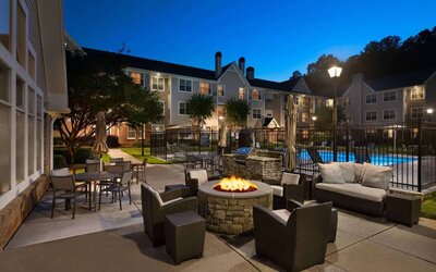 Patio area with fire pit, barbecue, tables and chairs, and armchairs, at Sonesta ES Suites Atlanta Alpharetta North Point Mall.