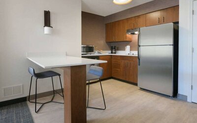 Sonesta ES Suites Fort Worth Fossil Creek guest room kitchen, featuring fridge-freezer, microwave, and table and chairs.
