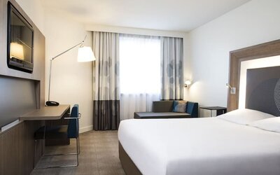 King bed with TV and sofa at Novotel Toronto North York.