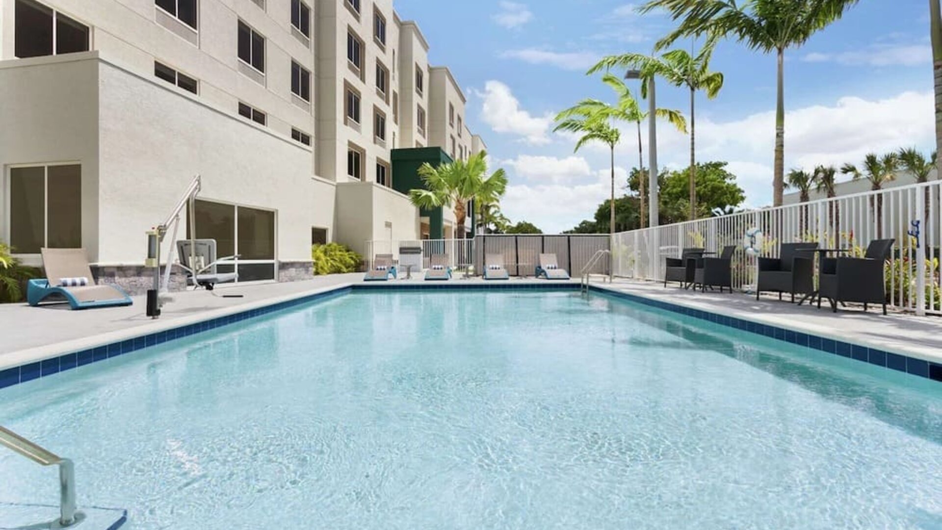 Outdoor pool with chairs at Hampton Inn & Suites Miami Kendall. 