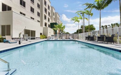 Outdoor pool with chairs at Hampton Inn & Suites Miami Kendall. 