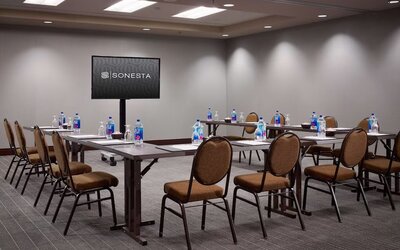 Hotel meeting room, with large table, seating for around 10 attendees, and a large widescreen television.