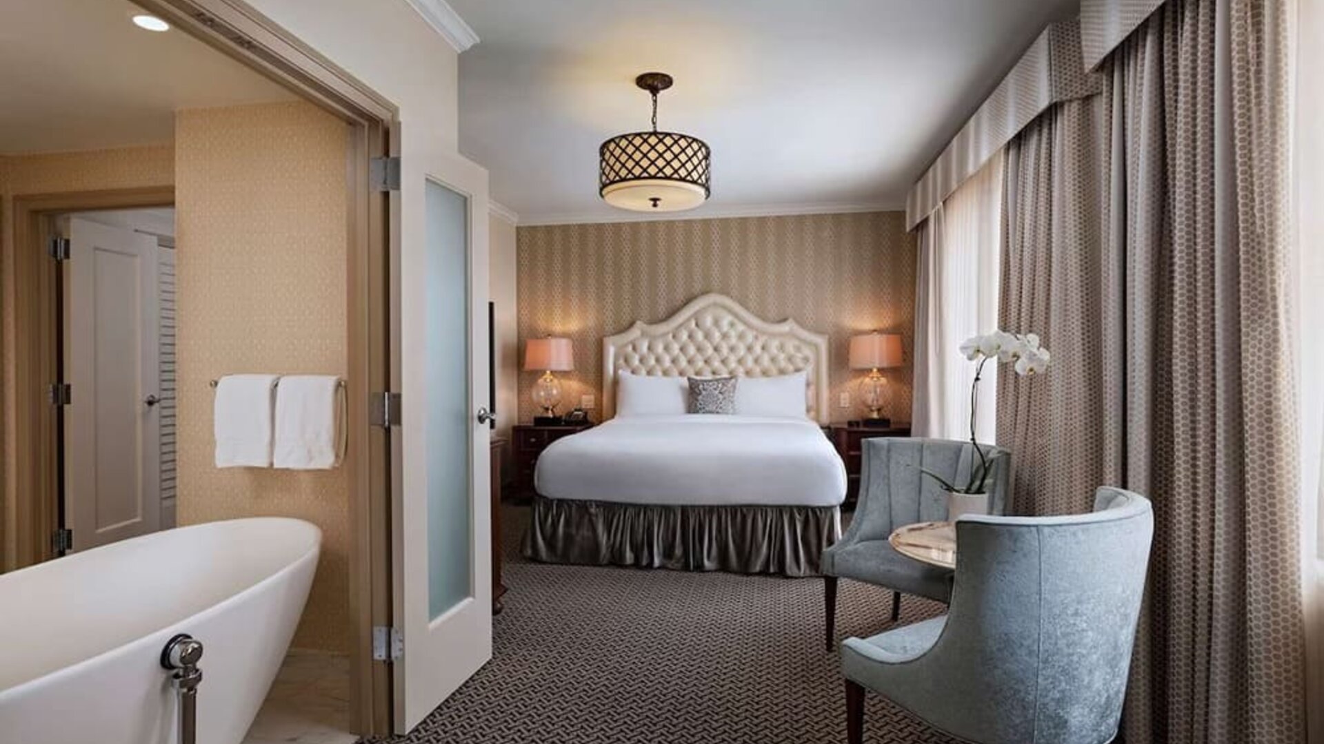 Double bed guest room lounge in The Stephen F Austin Royal Sonesta Hotel, furnished with sofa, television, and window.