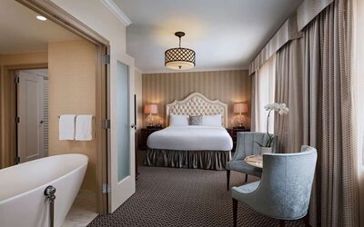 Double bed guest room lounge in The Stephen F Austin Royal Sonesta Hotel, furnished with sofa, television, and window.