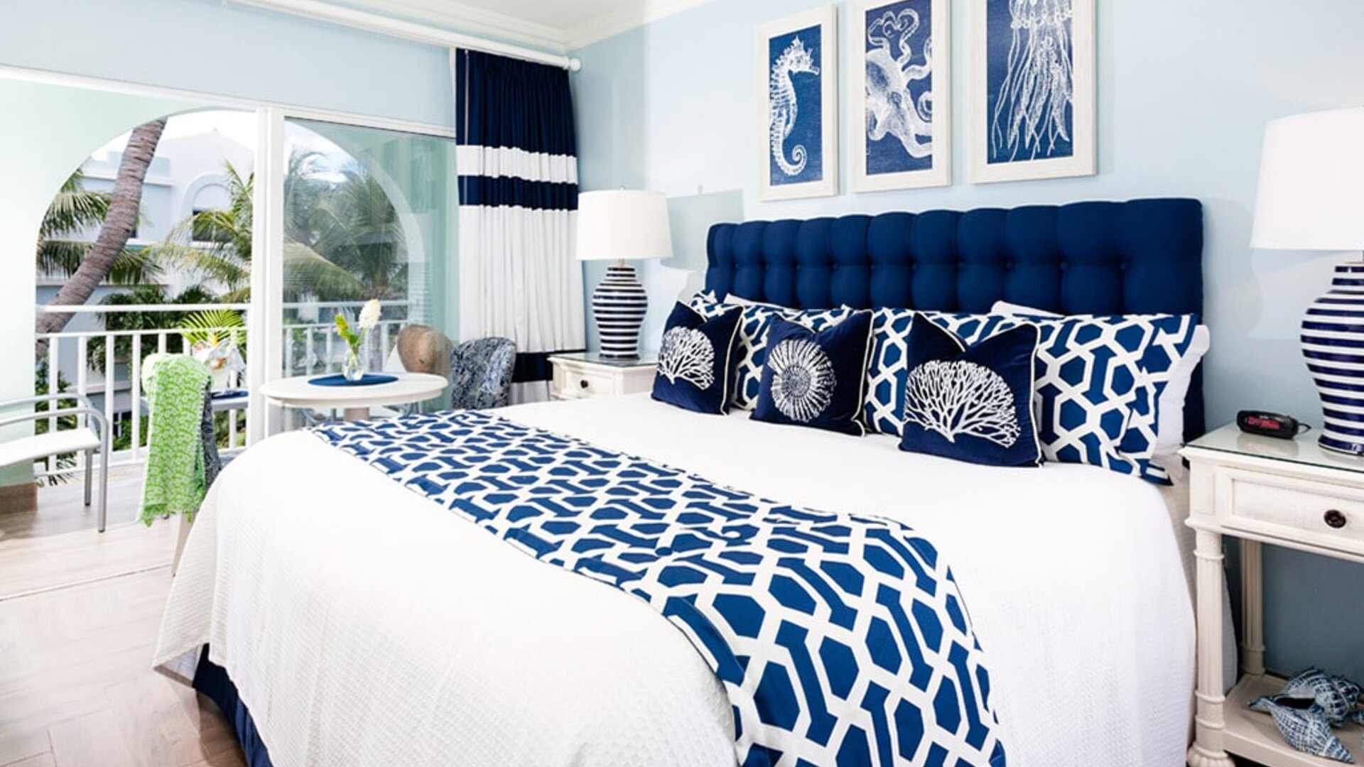 Bright dayroom with white and blue queen size bed and patio view at Oyster Bay Beach Resort. 