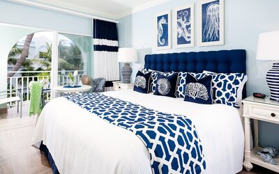 Bright dayroom with white and blue queen size bed and patio view at Oyster Bay Beach Resort. 