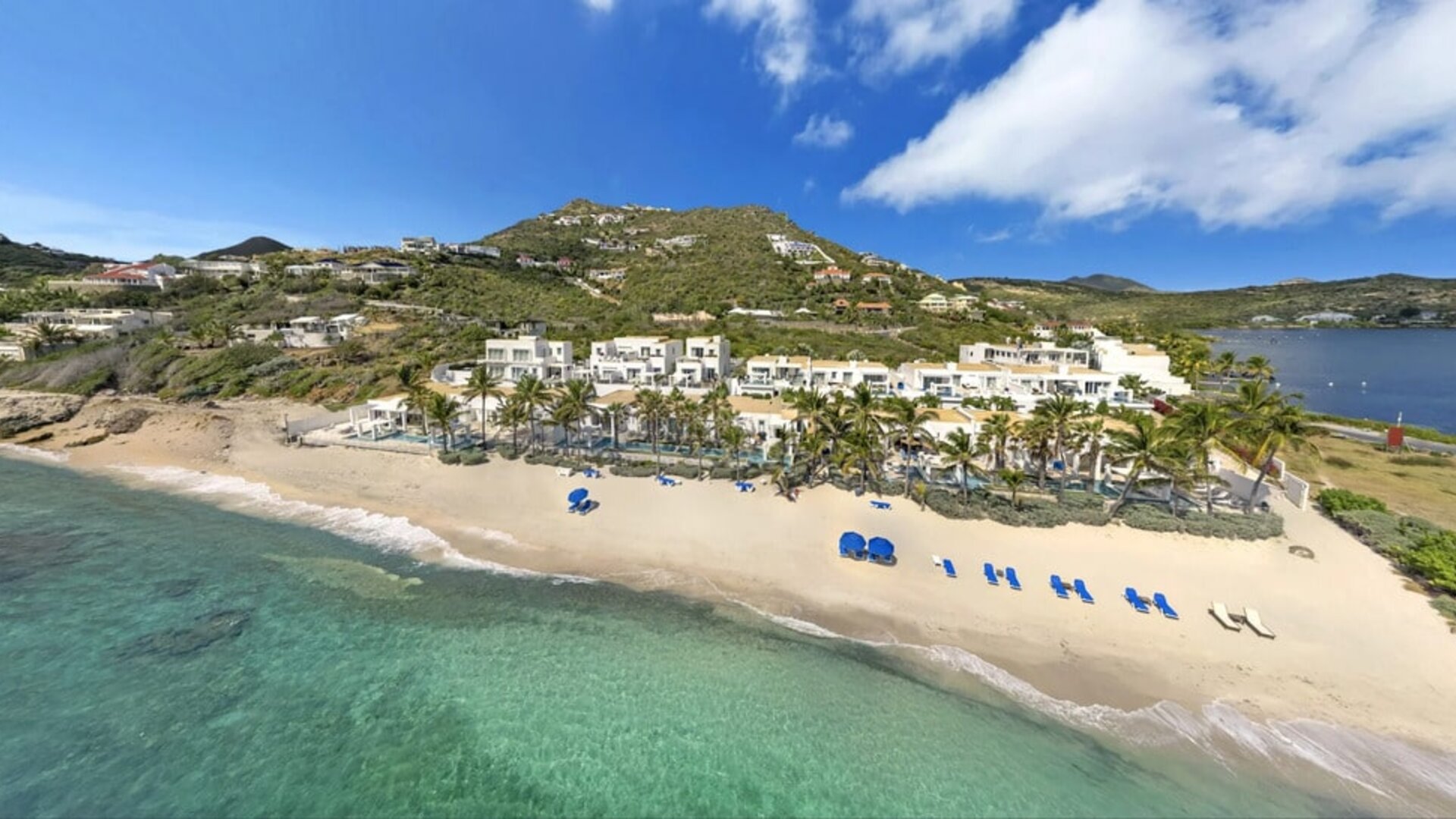 Oyster Bay Resort buildings, palm trees, coastline with tropical water shining. 
