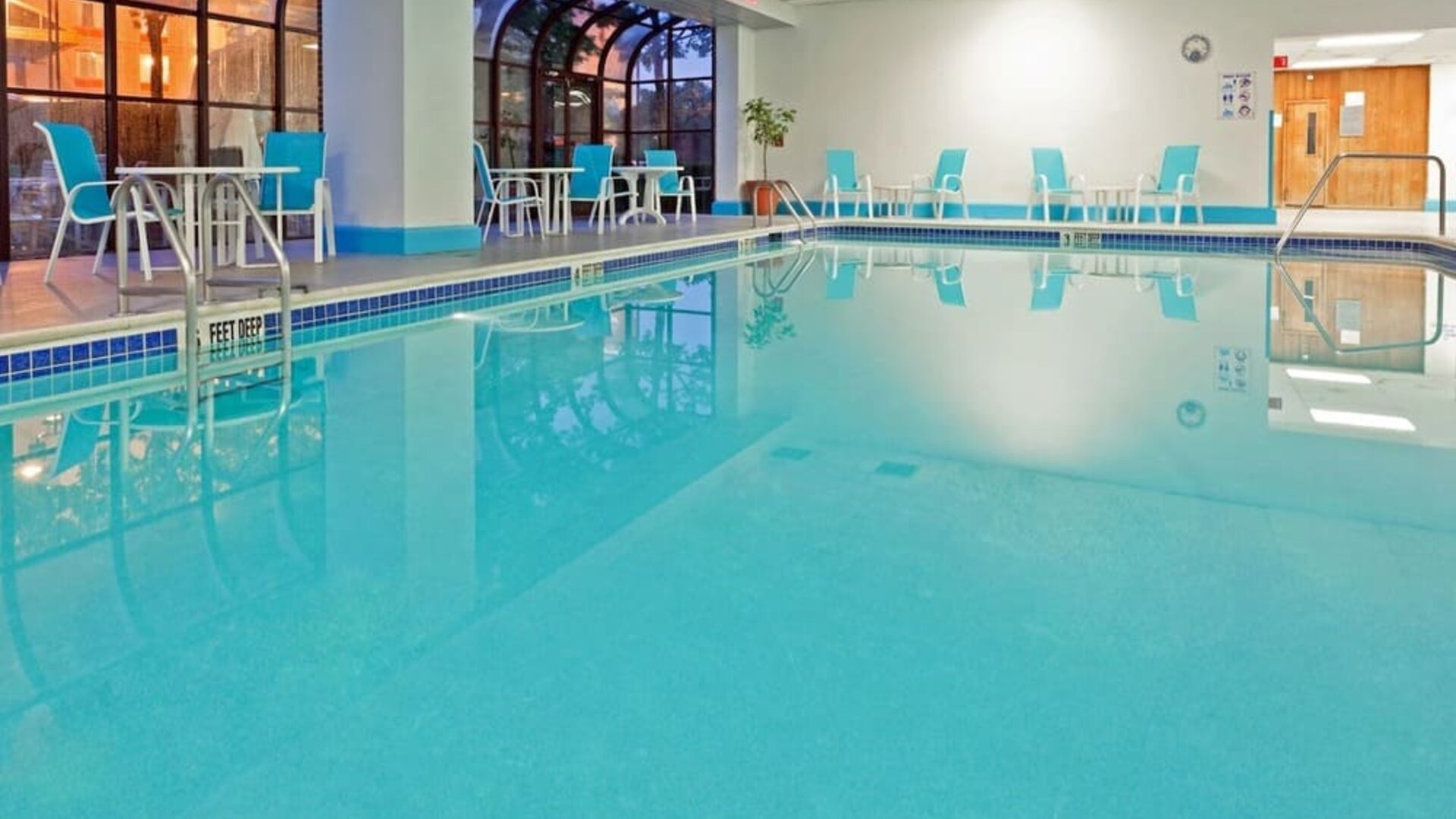 Indoor pool with seating area at Laguardia Plaza Hotel.