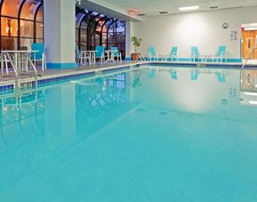 Indoor pool with seating area at Laguardia Plaza Hotel.