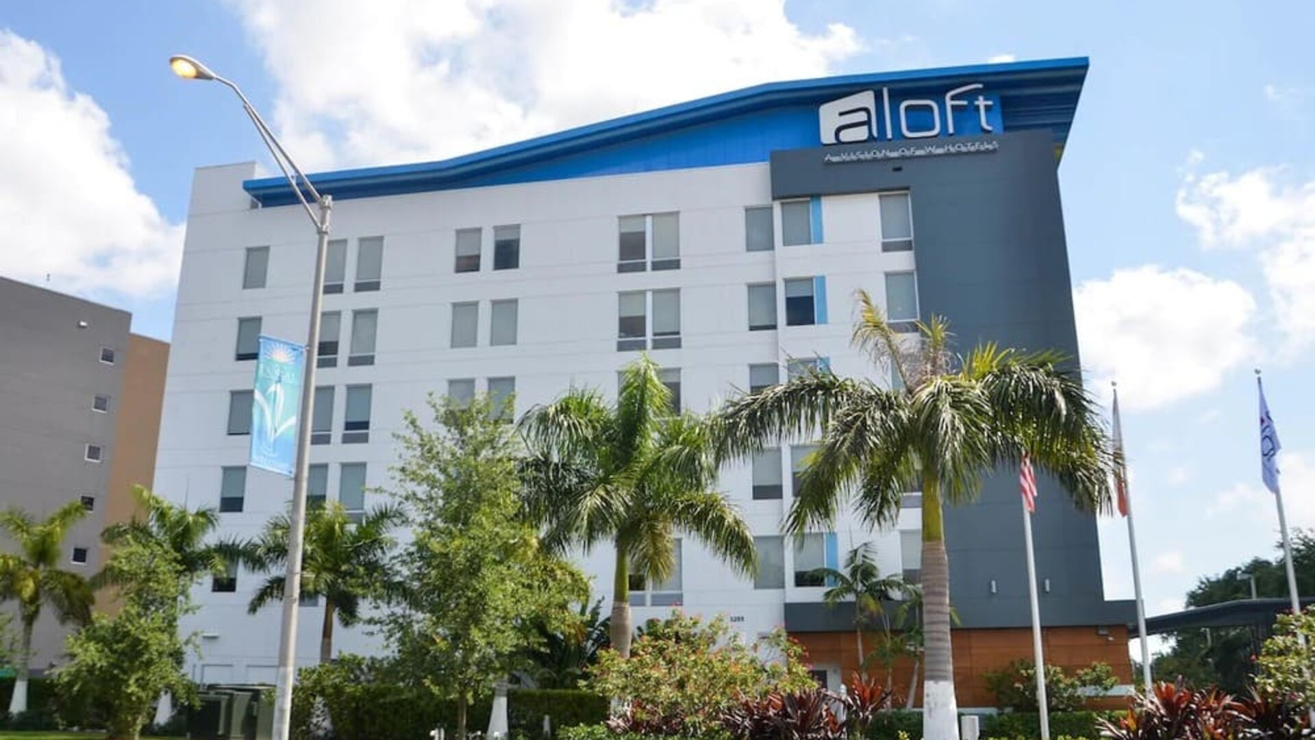 Hotel exterior with palm trees at Aloft Miami Doral.
