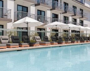 Outdoor pool with loungers and umbrellas at Lum Hotel Inglewood.
