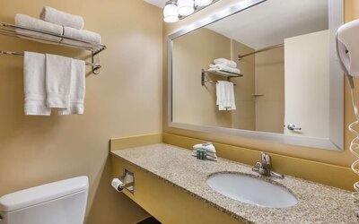 Modern guest bathroom featuring a granite vanity, large mirror, fresh towels, and complimentary toiletries at Best Western Braintree.
