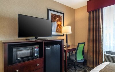 In-room workspace with desk, ergonomic chair, flat-screen TV, microwave, and mini refrigerator at Best Western Braintree.